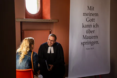 Pfarrer Ralf Haunert im Gespräch mit Michelle Kodym, die sich beim Tauffest "Segen spüren. Taufe erleben." in der Friedenskirche Kassel am 28. September 2024, taufen ließ