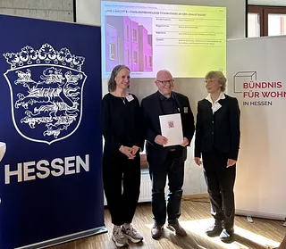Hessischer Preis für Innovation und Gemeinsinn im Wohnungsbau: Anerkennung für Wohnprojekt auf Kirchengrundstück in Kassel. Freuen sich über die Anerkennung beim Hessischen Preis für Innovation und Gemeinsinn: (v. l.) Laudatorin Gabriele Schmücker-Winkelmann, Vizepräsidentin der Architekten- und Stadtplanerkammer Hessen, Prof. Alexander Reichel, Reichel Architekten (Kassel) und Iris Otto, Abteilungsleiterin Bauen, Wohnen, Städtebau im Hessischen Ministerium für Wirtschaft.